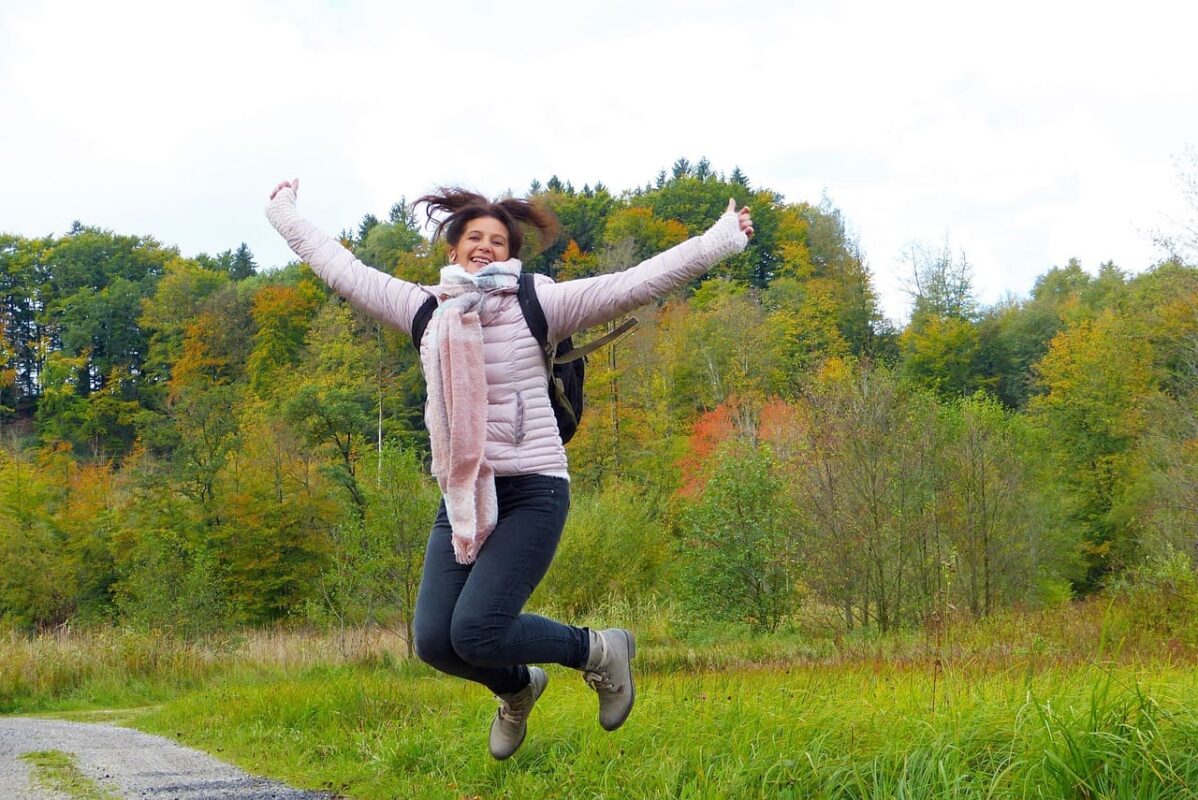 donna che salta in mezzo alla campagna autunnale